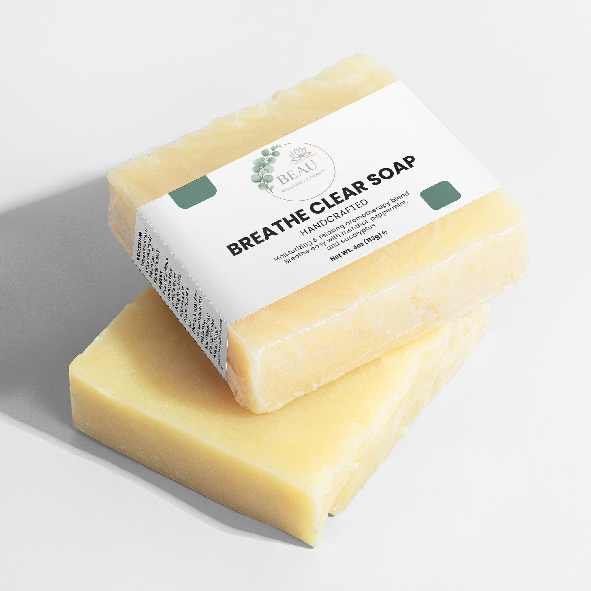 Two bars of Beau Wellness & Beauty Breathe  clear soap with perppermint and eucalyptus with  a visible label on a light background