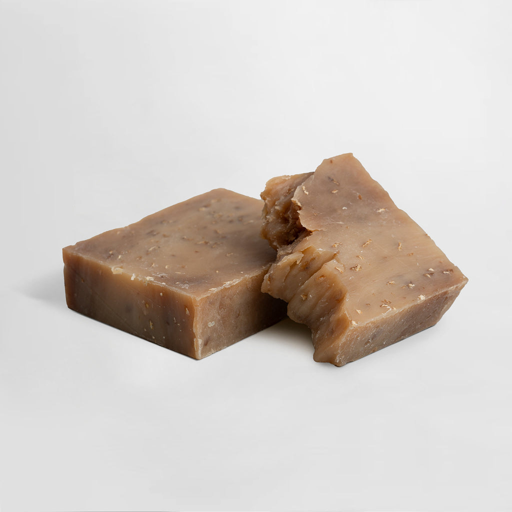 Two pieces of oat milk & Honey handcrafted soap on a light gray background