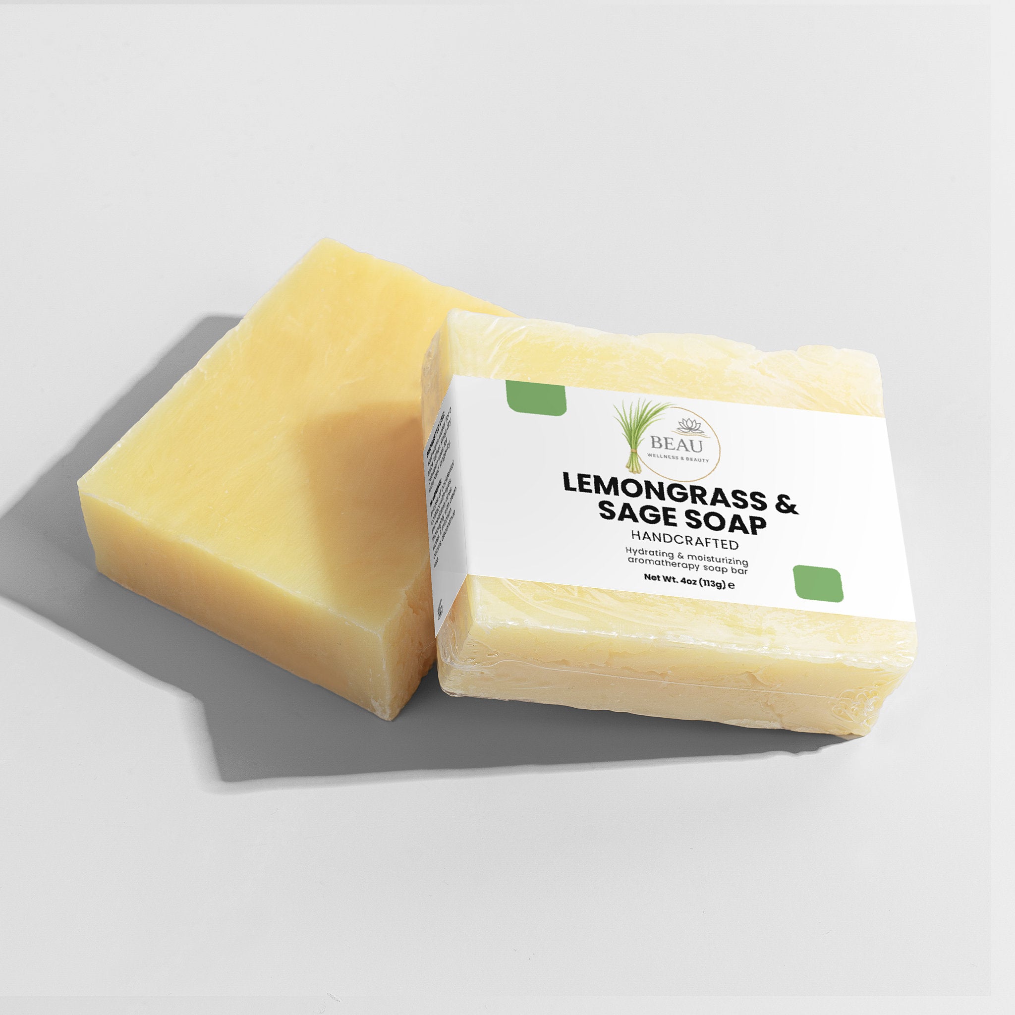 Two handcrafted bars of lemongrass and sage soap with a Beau Wellness & Beauty label on a light gray background