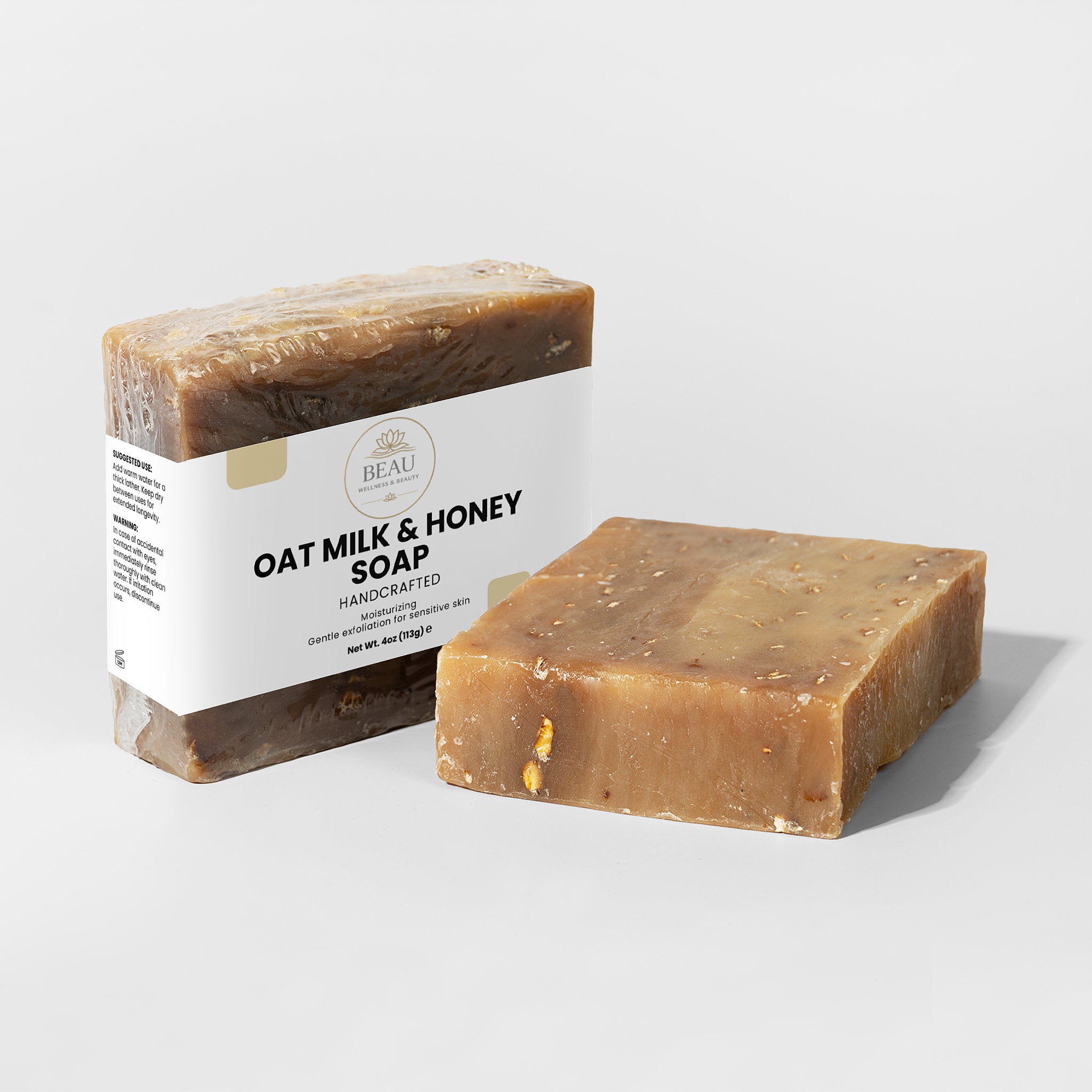 Two handcrafted  bars of oat milk and honey soap with a  Beau Wellness & Beauty label on a light gray background