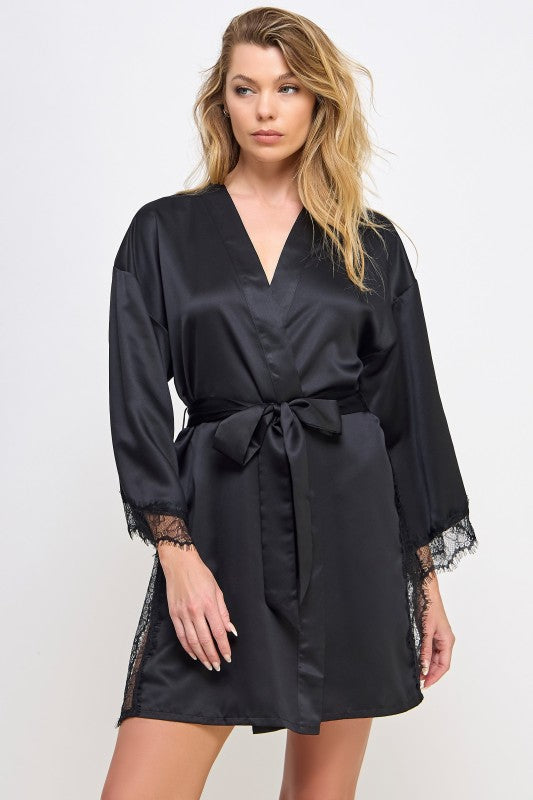 Woman wearing a black  satin robe with lace trim on a white background