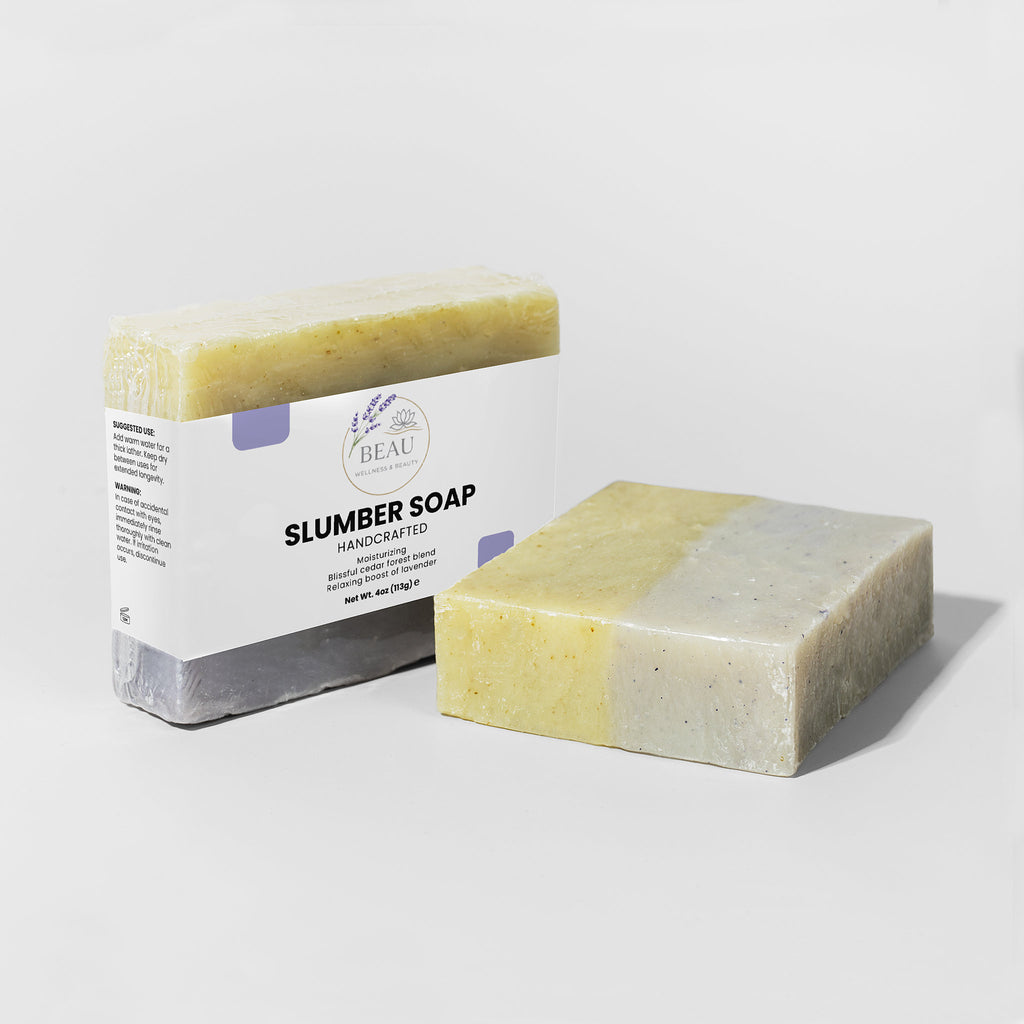 Two bars of handcrafted Slumber soap with cedar and lavender with a packaging box labeled 'Slumber Soap' on a white background.