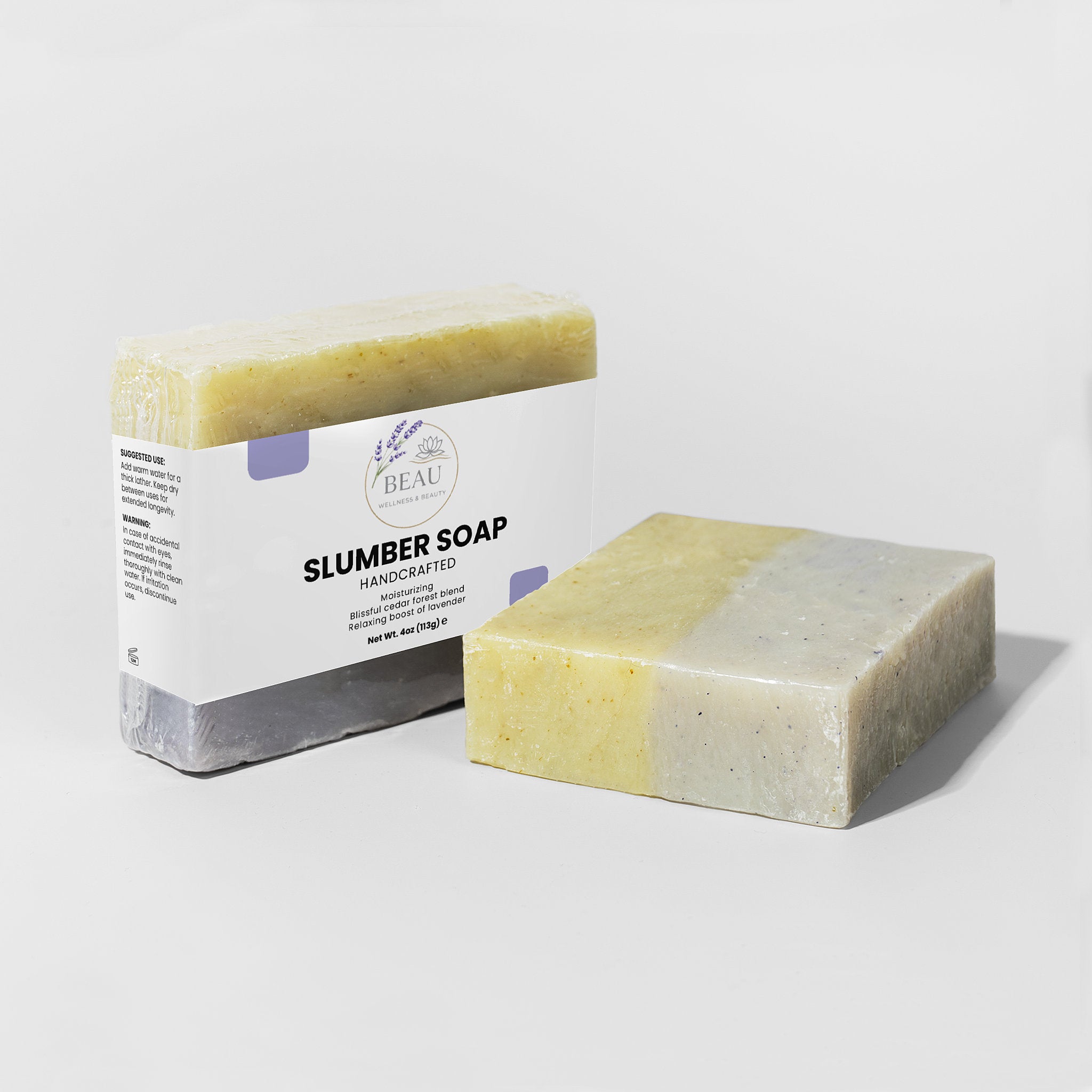 Two bars of handcrafted Slumber soap with cedar and lavender with a packaging box labeled 'Slumber Soap' on a white background.
