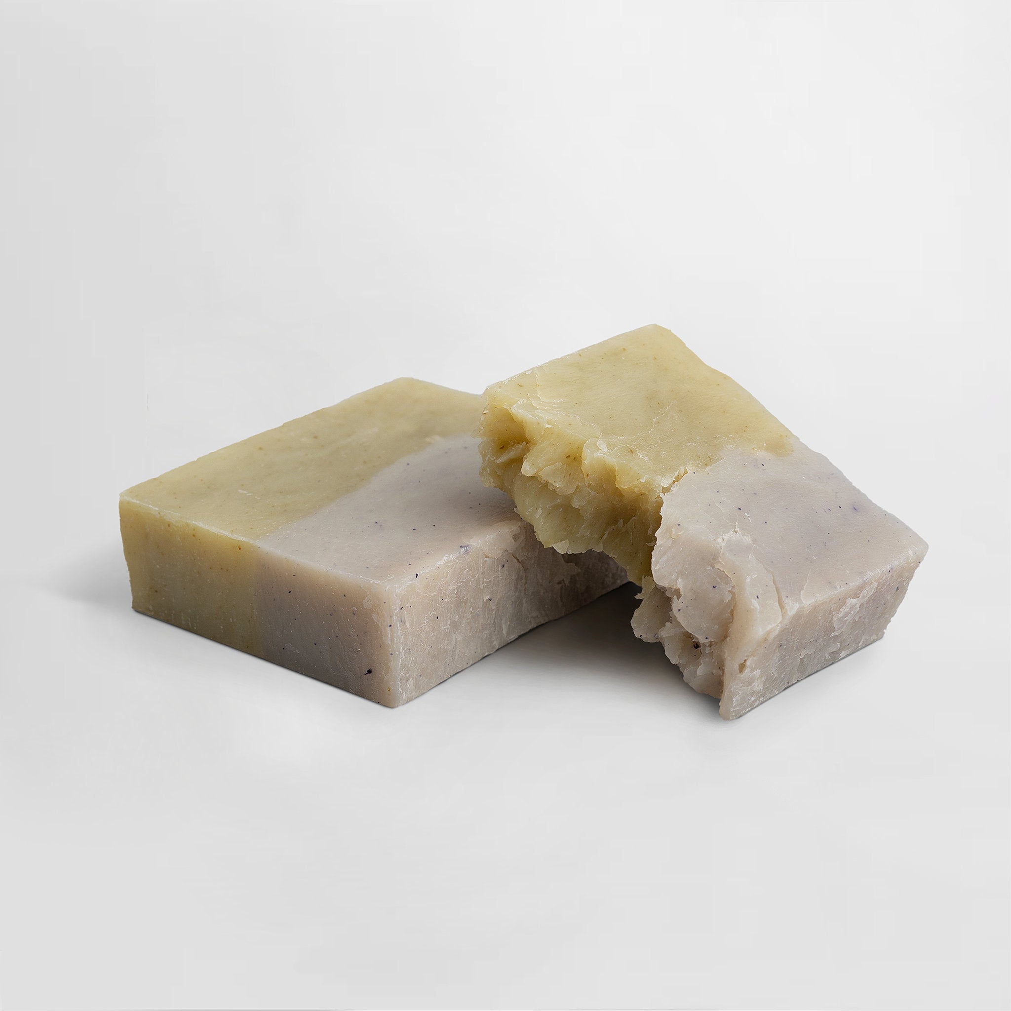 Bar of handcrafted Slumber soap with cedar and lavender with a piece missing on a light gray background