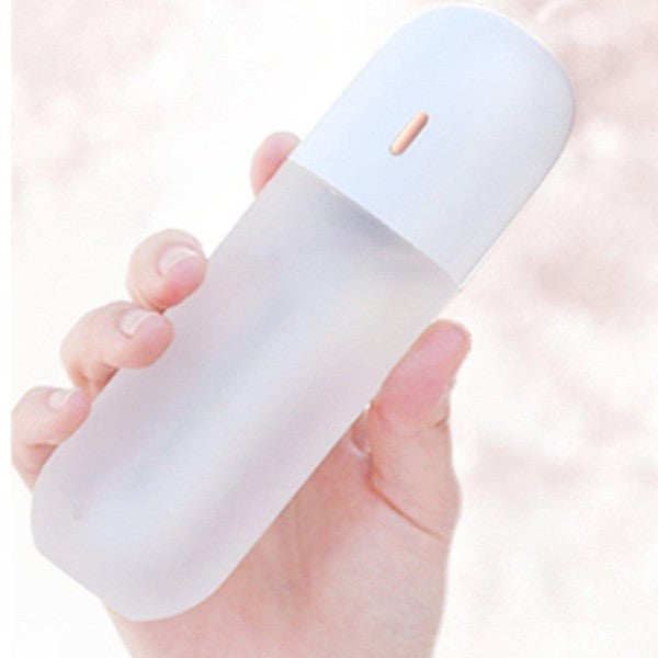 Hand holding a white Anywhere Portable Bottle Humidifier.