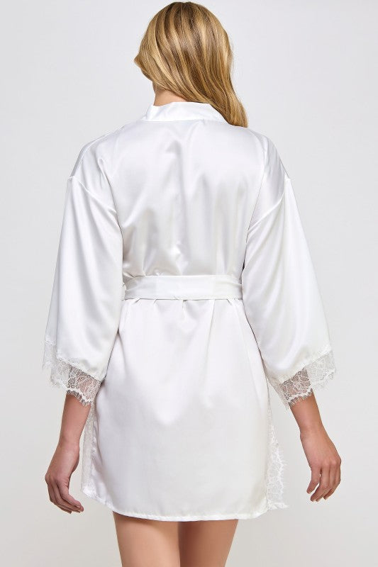 White satin robe with lace cuffs and hem on a plain background