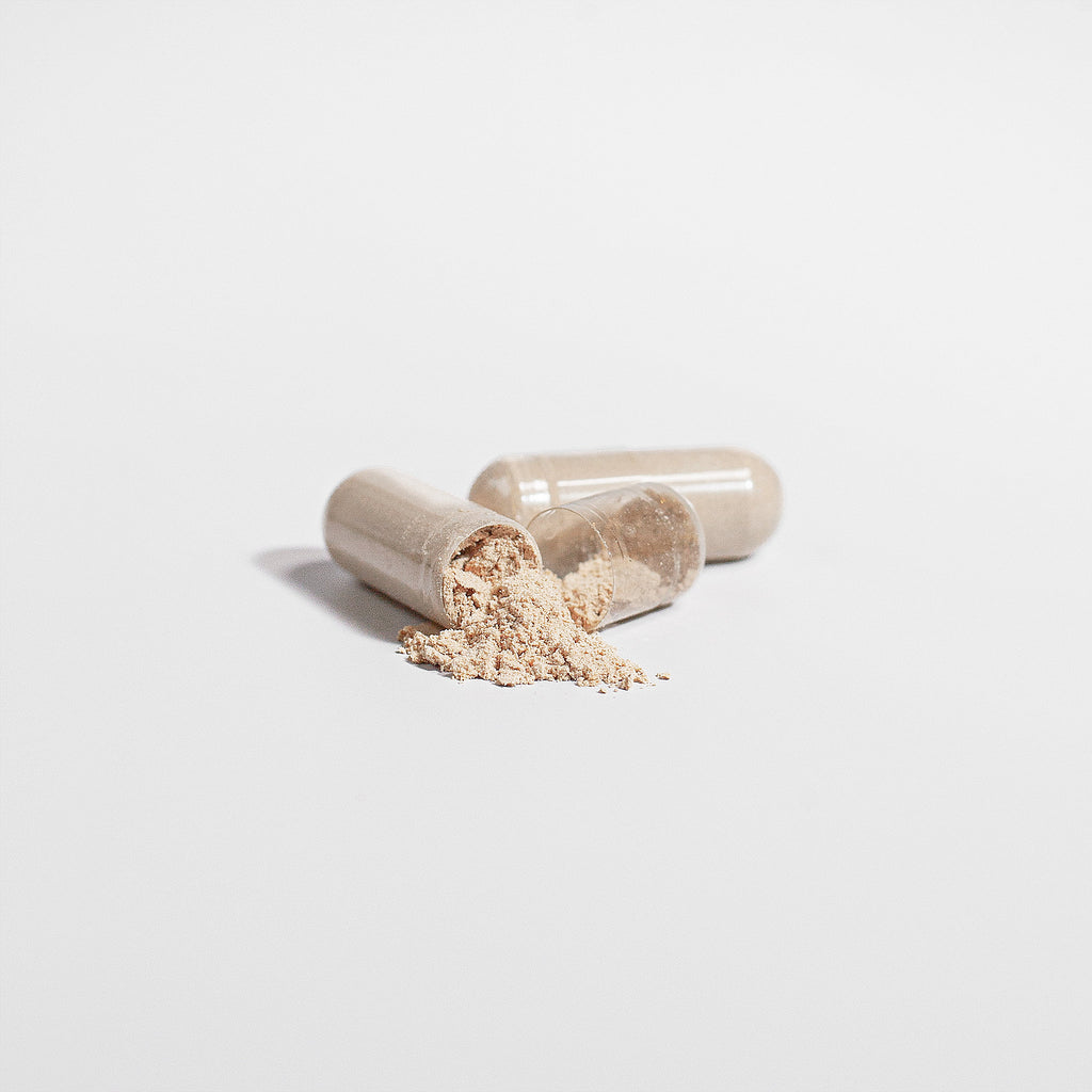 Two loose capsules of Beau Wellness Organic Lions Mane Mushroom Vegan Capsules for Focus and Memory⁠ on white background.