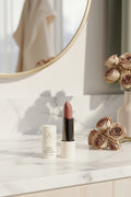 Lipstick with 'Beau Wellness & Beauty packaging on a light marble bathroom counter with mirror in the background
