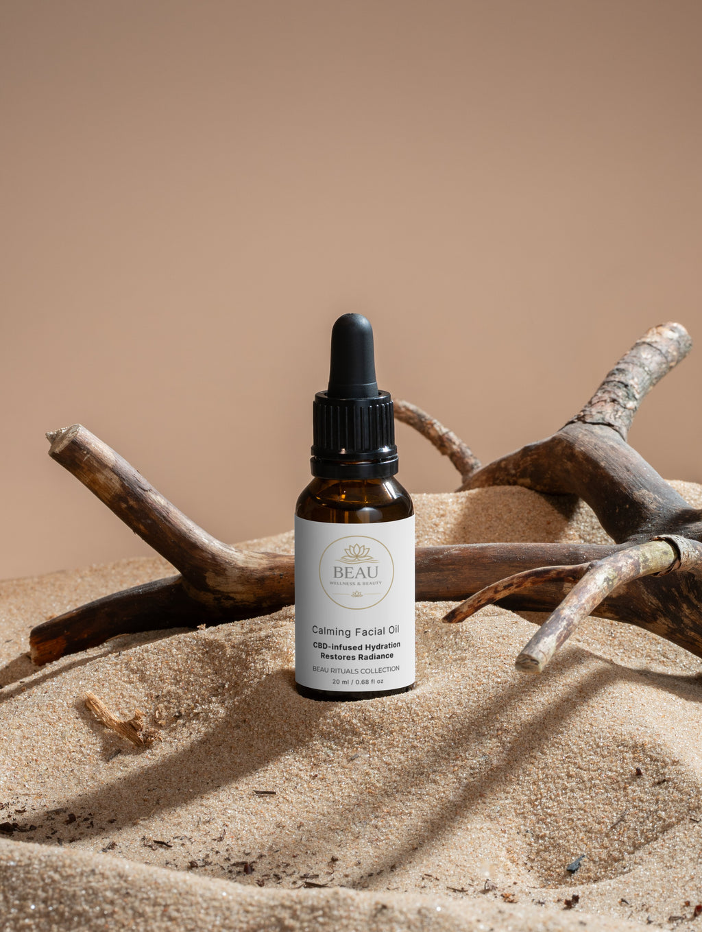 Beau calming facial oil skin dropper bottle on a sandy surface with driftwood