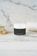 Jar of Beau Wellness & Beauty Deep Cleanse Scalp Scrub with Rosemary & Mint with a black label with a white top on a white marble background with soap and towel.
