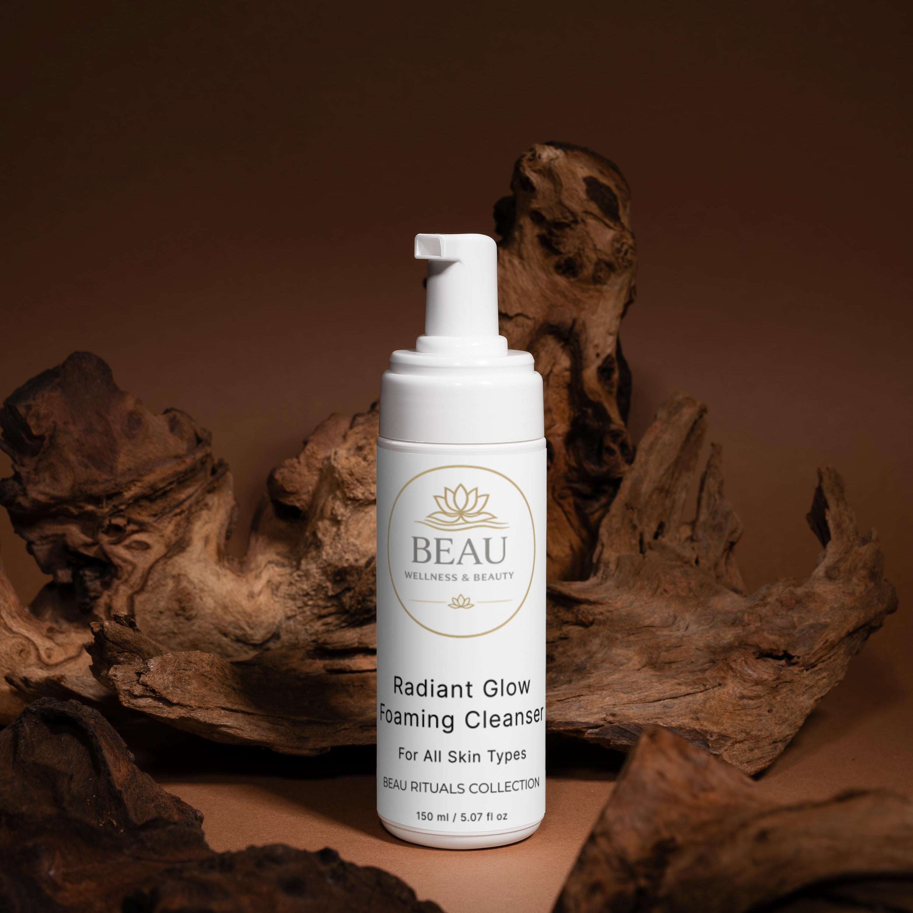 White bottle of Beau Wellness & Beauty Radiant Glow Foaming Cleanser skincare product on a brown background with natural elements.