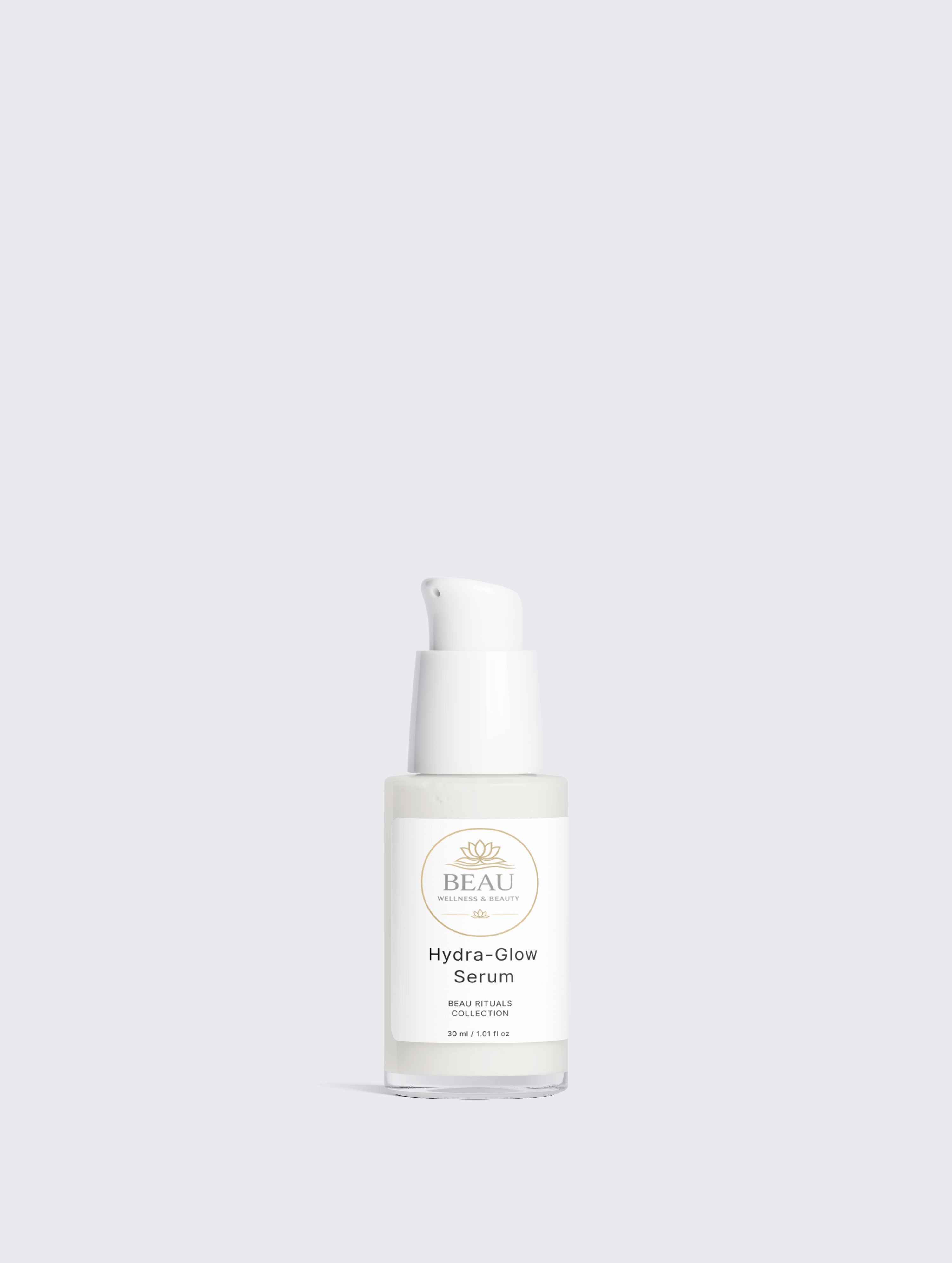 A clear glass bottle of BEAU Wellness & Beauty Hydra-Glow Serum with a white pump dispenser and a white label, centered against a solid light gray background.