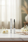 Beau Wellness & Beauty Lengthening and Volumizing Mascara peptide infused on marble counter with white roses and baby fresh.
