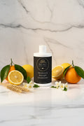 Beau Wellness & Beauty  Moisture & Strength Conditioner on a white marble background with citrus fruits, wheat stalks and jasmine flowers.