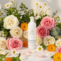 BEAU Wellness & Beauty Radiant Glow Foaming Cleanser skincare bottle surrounded by flowers on a light background