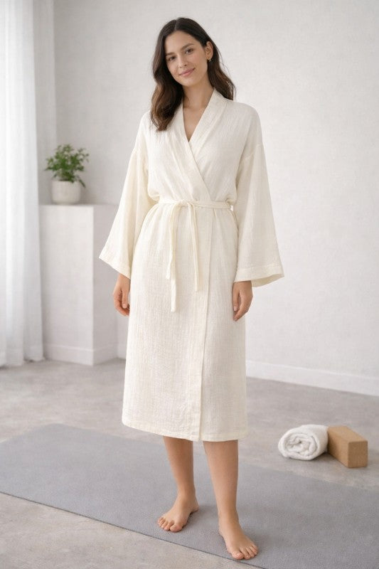 Woman wearing a white Cotton Muslin Wrap Robe in a minimalistic room.