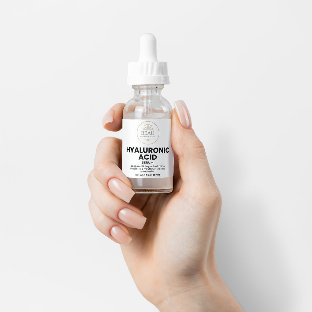 A glass bottle of Beau Wellness & Beauty Hyaluronic Acid Serum with a white dropper cap, featuring a clean label that highlights deep multi layer hydration for a youthful-looking complexion held by hand