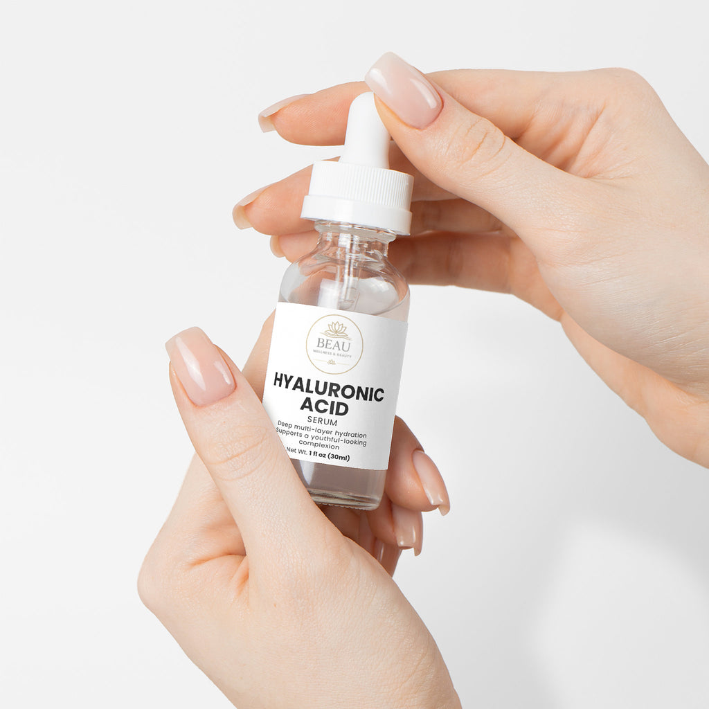 A glass bottle of Beau Wellness & Beauty Hyaluronic Acid Serum with a white dropper cap, featuring a clean label that highlights deep multi layer hydration for a youthful-looking complexion held by two hands.