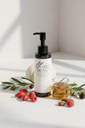 Beau Wellness & Beauty Radiant Ritual Omega 6 9 Oil with rosehip, raspberries, olive branches, almonds, a small white pumpkin behind the bottle and oil.